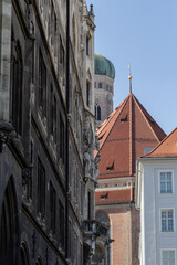 The tower of Frauenkirche in Munich, Germany, seen through surrounding buildings, offering a unique view of the city's architecture.