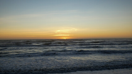 Tranquilo atardecer sobre el océano con cielo dorado y suaves olas