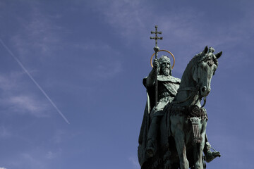 The Statue of St. Stephen in Budapest with a plane flying in the background, highlighting the blend of history and modernity.
