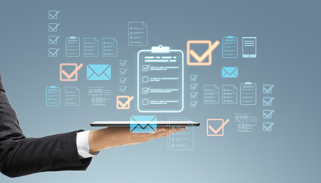 Business professional holding tablet with digital holographic interface of files, checklists, and emails.