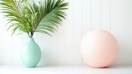 An elegant arrangement featuring a soft pastel vase with palm leaves and a modern sculptural peach sphere, creating a tranquil and artistic interior decor statement.