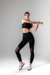 Young woman stretching in activewear against a neutral background during a fitness session