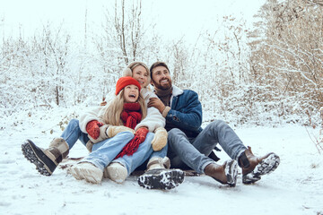 Obraz premium Cute young family having fun in a winter forest and looking enjoyed