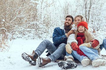Obraz premium Cute young family having fun in a winter forest and looking enjoyed