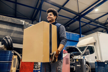 Smiling multicultural worker carrying box at import and export firm.