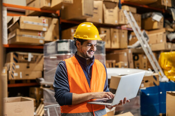 Cheerful interracial storage worker with laptop typing on it and using drop shipping app.