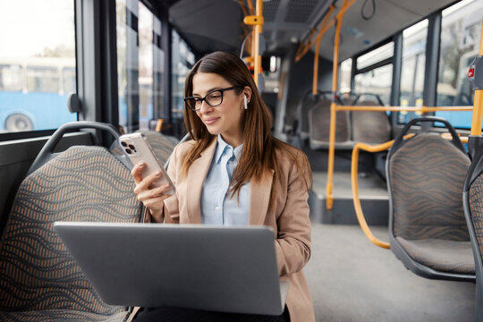 Portrait of trendy lady riding city bus and using laptop and her phone. Cutting edge technologies. - Powered by Adobe