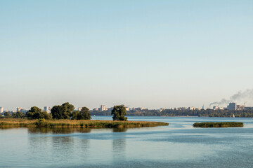 Small islands emerging from wide river with city in background