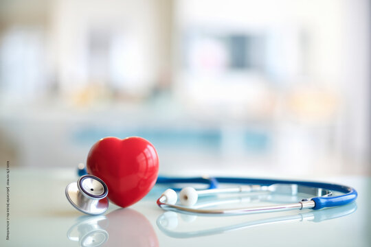 Red heart love shape hand exercise ball with doctor physician's stethoscope on hospital background: Hospital life insurance concept: World heart health day. doctor day, world hypertension day