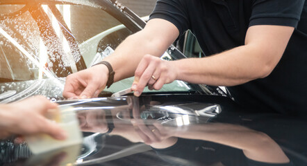 A car wrapping specialist applies a polyurethane film to the car. Selective focus. PPF protective film against chips and scratches. Armored film on the car mirror. Car wrapping close-up.