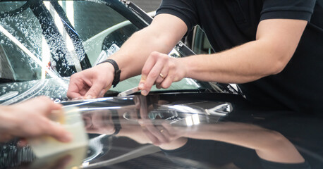 A car wrapping specialist applies a polyurethane film to the car. Selective focus. PPF protective film against chips and scratches. Armored film on the car mirror. Car wrapping close-up.
