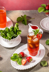 Refreshing strawberry iced tea with fresh mint and ice cubes on a table