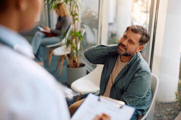 Mature man talking about his medical condition with doctor at clinic.