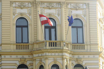 Fototapeta premium The Austrian Consulate in Belgrade (Serbia), housed in a historic 19th-century building: a close-up photograph of the facade with rich decoration and flags of the European Union and Austria