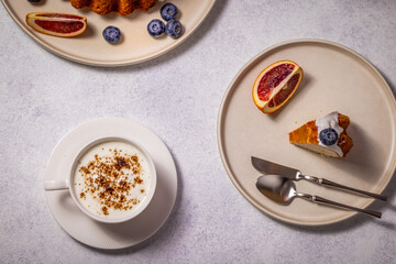 Delicious cake with cappuccino, orange, and blueberries on table