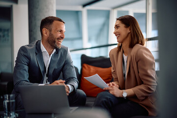 Happy businesswoman and her colleague talking while working in office.