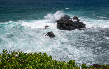 Dramatic ocean waves crashing against volcanic rocks. Wild seascape with waves breaking on dark rocky outcrop.Powerful ocean surf meeting volcanic shoreline