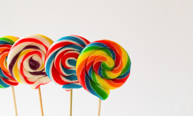 Colorful stick, spiral lollipop candies on white surface standing with copy space