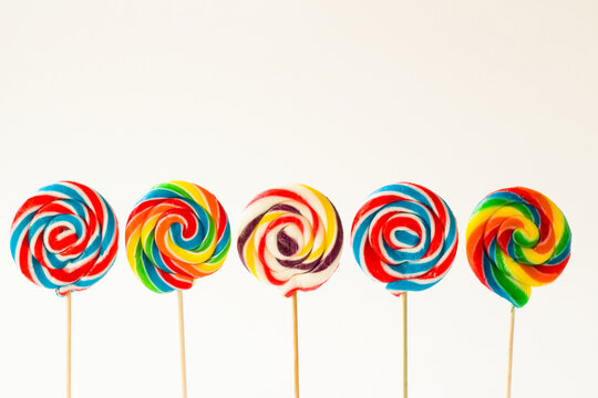 Colorful stick, spiral lollipop candies on white surface standing with copy space