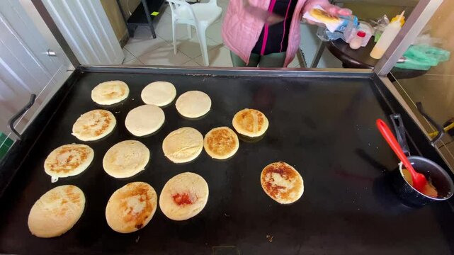 Seller cook Arepas, flatbread made of maize corn, to serve for customers at a small stall in Bogota, Colombia.