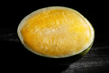 sliced yellow watermelon on black wood background