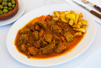 Appetizing baked pork cheeks served with potato and vegetables on plate