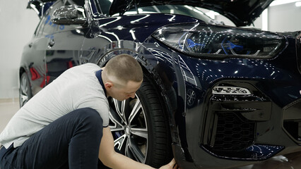 Car fender repair in a car service. The mechanic is focused on the work. Detailing and inspection...