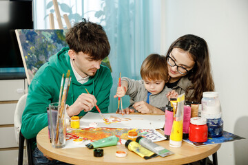Young family with their son painting and having fun in the room