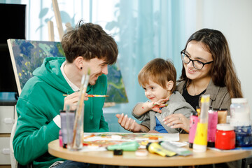 Young family with their son painting and having fun in the room