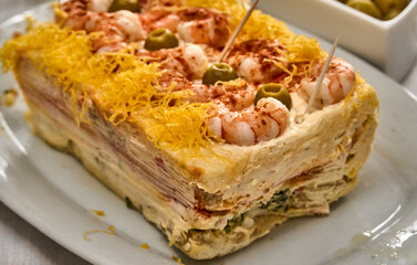 Cold seafood cake garnished with shrimp, olives, and egg threads
