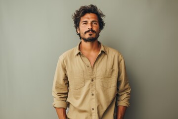 A man with a beard and mustache is wearing a tan shirt