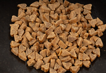 Mini pet food shaped like hearts in bowl close up, small dogs crunchy treats pile macro