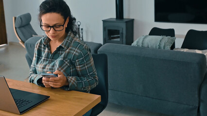 Woman Working Remotely from Home Using Smartphone and Laptop