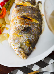 Appetizing roasted dorada served with baked asparagus, tomatoes and onion garnished with cranberries