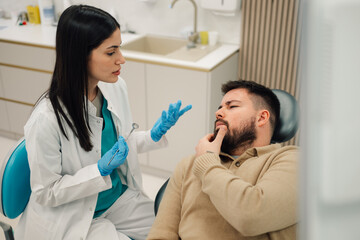 Dentist explaining diagnosis to patient having toothache in dental clinic