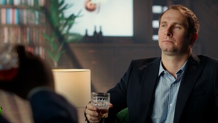 Old money classy heir drinking a glass of whiskey at elite social club, thinking about an opportunity to double his fortune. Elegant upper class billionaire gentleman sipping alcohol. Camera B.