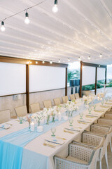 Set festive long table with a strip of blue fabric in the middle with bouquets of flowers