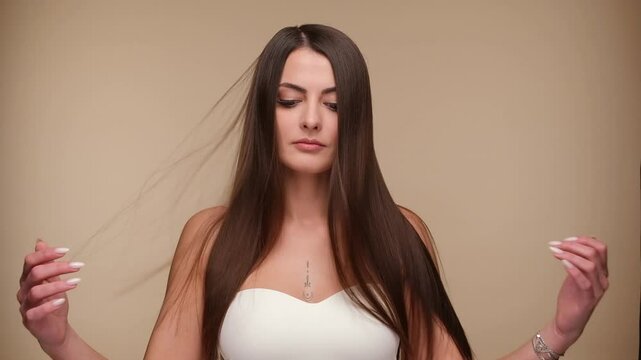 Beautiful woman with brown healthy hair on beige background. Hair beauty.