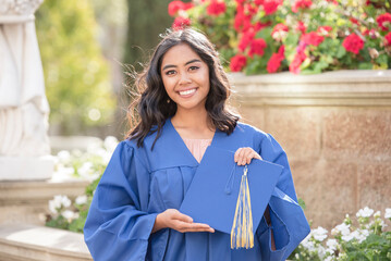 Asian high school graduate holding her cap and wearing her gown