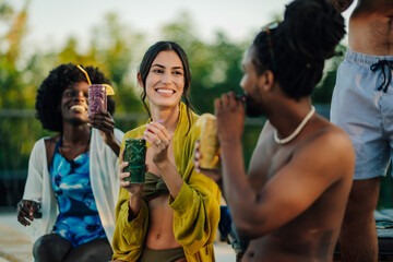 Friends enjoying cocktails by swimming pool during summer holidays
