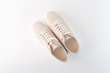 Beige canvas sneakers with white laces on a white background. Flat lay composition with copy space. Footwear, fashion, and lifestyle concept for design and print,