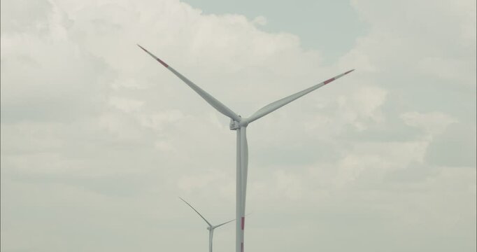 Wind turbine rotating blades generating green energy under cloudy sky