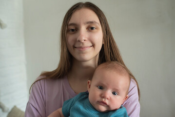 young woman or teenage girl holding her baby brother in her arms. focus on girl.