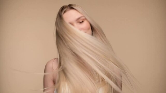 Beautiful woman with blond healthy hair on beige background. Hair beauty.