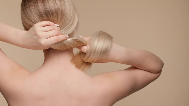Beautiful woman with blond healthy hair on beige background. Hair beauty.