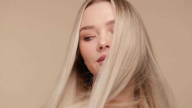 Beautiful woman with blond healthy hair on beige background. Hair beauty.
