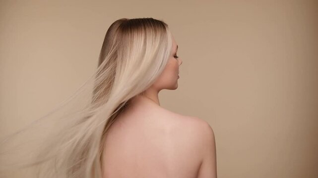 Beautiful woman with blond healthy hair on beige background. Hair beauty.