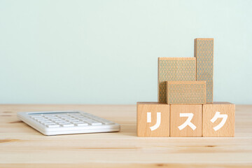 リスクと書かれたブロック、不動産の模型、電卓