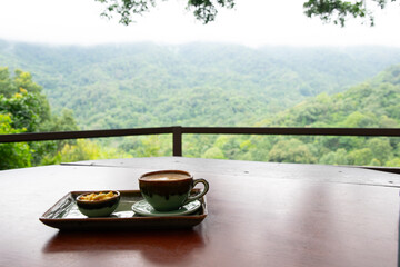 Tray with a cup of coffee and a bowl of food sits on a wooden table