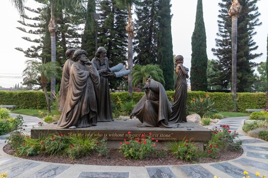 Bronze statues depict the biblical story of Jesus and the adulterous woman, with the inscription "Let he who is without sin cast the first stone" in California, USA. 15 September 2024